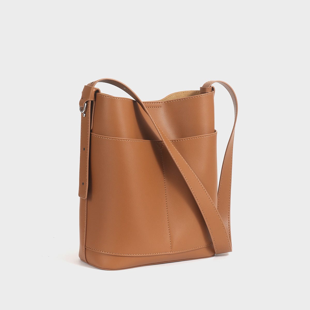 a tan leather bucket bag with a long strap